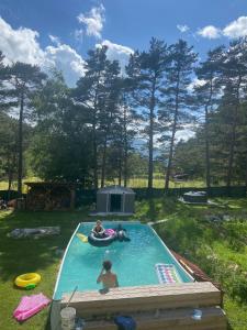 two people in a swimming pool in a backyard at Chalet for 10 with the forest in Séranon