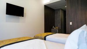 ein Hotelzimmer mit zwei Betten und einem Flachbildfernseher in der Unterkunft Hotel Pasha in Mostar