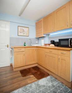 a kitchen with wooden cabinets and a microwave at The Annex @ 136 in Gloucestershire
