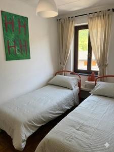 two beds in a room with a window at Appartamento Lucia in Ampezzo