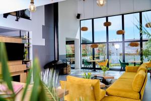 a living room with yellow furniture and large windows at BlackBird Hub in Arad