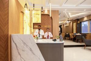 two people standing at a counter in a lobby at Hotel Aroma Suites Delhi - With Free Airport Drop in New Delhi