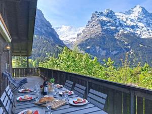 a table with plates of food on a balcony with mountains at Chalet Egg-Isch by Interhome in Grindelwald