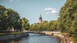 a river in a park with a bridge and a tower at Original Sokos Hotel Wiklund in Turku