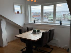 a dining room with a wooden table and windows at Rooftop view apartment 2 in Vardø