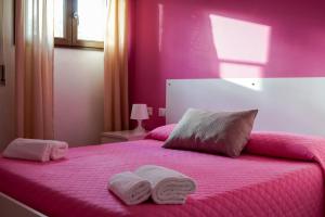 ein rosa Schlafzimmer mit zwei Handtüchern auf einem Bett in der Unterkunft Sole D'oriente in Palmi + 49 Fotos