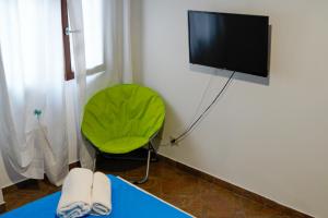 ein Zimmer mit einem grünen Sessel und einem Flachbildfernseher in der Unterkunft Sole D'oriente in Palmi