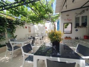 a restaurant with white tables and chairs and plants at Nese Otel in Çeşme