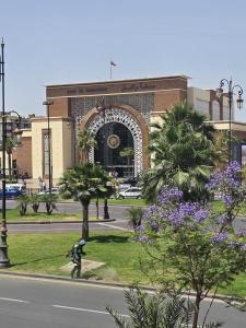 a man walking a dog in front of a building at Hôtel Résidence Marrakech in Marrakesh