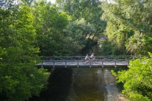 two people walking across a bridge over a river at Apartma Rižana in Dekani