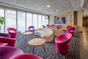 a room with pink chairs and tables and a tv at Park Hôtel & Appartements in Cholet