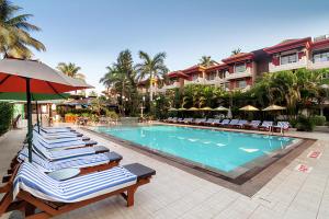a row of lounge chairs next to a swimming pool at a resort at Somy Plaza Calangute Goa - Formerly Somy Resort in Calangute
