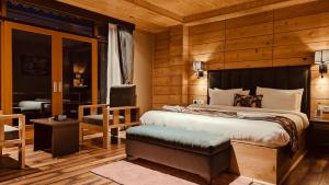 a bedroom with a large bed and a chair at Valmere Bayul Shangri-La Resort in Lachung