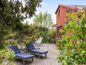 a patio with blue chairs and a red building at Holiday Home Ringenäs by Interhome in Halmstad