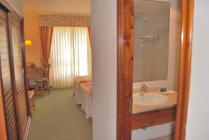 a bathroom with a sink and a bed and a mirror at Hotel Spa Bosque Mar in Reboredo +85 photos