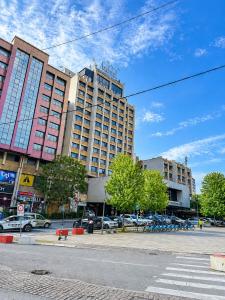 a large building with cars parked in a parking lot at The Square Central Prishtina in Prishtinë