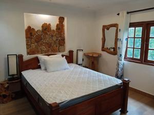 a bedroom with a large bed with white sheets at The Wood Cottage in Elkaduwa