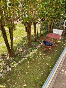 a red table and chairs in a yard with trees at Le studio rock in Orthez