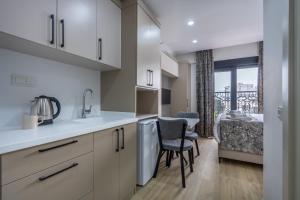 a kitchen with white cabinets and a table with a chair at Daylights Apart Otel in Antalya