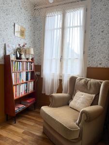 a living room with a chair and a book shelf at Maison Bécharie in Uzerche