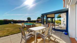 a patio with a table and chairs and a pool at Villa BlueGreen in Coëx