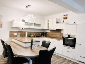 a kitchen with white cabinets and a wooden table with chairs at Ferienwohnung Meeresblick Haus Granitz in Prora in Binz