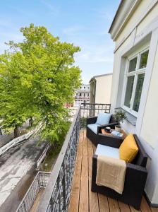 a balcony with two couches and a tree at Stilvolles Apartment mit Wintergarten, Balkon & Parkblick - VILLA KAETHE am Kurpark in Warnemünde