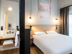 a bedroom with a large white bed and a sink at ibis Styles Namur in Namur +113 photos