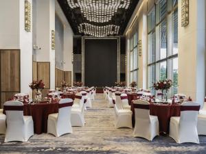 a large banquet hall with tables and white chairs at Sofitel Haikou in Haikou