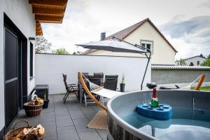 a bath tub on a patio with an umbrella at Familienfreundliche Ferienwohnung mit großem Garten, Spielplatz, privatem Badefass & Sauna in Wendisch Rietz