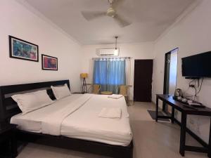 a bedroom with a large bed and a desk at Baga Central Studio Apartment in Baga
