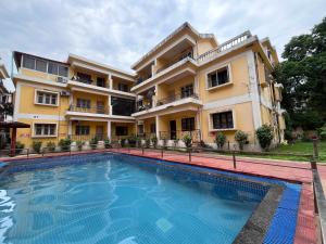 a hotel with a swimming pool in front of a building at Baga Central Studio Apartment in Baga
