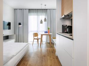 a kitchen with white cabinets and a table with a chair at smartments Berlin Karlshorst in Berlin