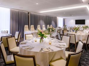 a banquet room with white tables and chairs at Mövenpick Hotel Hobart in Hobart