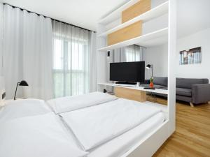 a white bedroom with two beds and a tv at smartments Berlin Karlshorst in Berlin