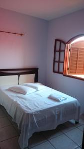 1 dormitorio con 1 cama con sábanas blancas y ventana en Pousada Portal da Ilha en Itaoca