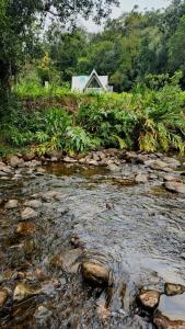 a stream with a house in the background with a house at Chalé Villa Mount in Timbe do Sul