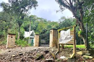 a sign in front of a fence with a yard at Chalé Villa Mount in Timbe do Sul +2 photos