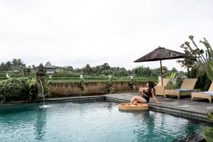 a woman sitting on a boogie board in a swimming pool at Padi Bali Villa With Private Jacuzzi in Payangan