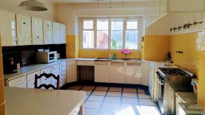 a kitchen with yellow walls and white cabinets at Charmant gîte vosgien avec 13 chambres pour 30 personnes in Fellering