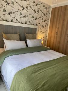 a bedroom with a large bed with a bird wallpaper at EdenNest in Boksburg +24 photos