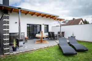 a patio with a table and chairs and a fireplace at Fewo River, Stilvolles Ferienhaus für Familien großer Garten, Spielplatz, Sauna & Badefass in Wendisch Rietz