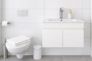 a white bathroom with a toilet and a sink at Ado Pension in Wedel +32 photos