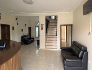 a living room with black leather furniture and a staircase at Gorilla Trekking Guest House in Ruhengeri