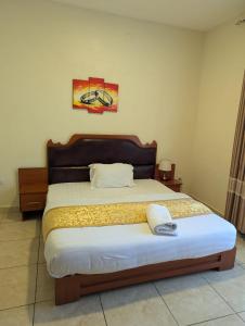 a bedroom with a large bed with a wooden headboard at Gorilla Trekking Guest House in Ruhengeri +16 photos