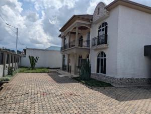 a large white house with a brick driveway at Gorilla Trekking Guest House in Ruhengeri
