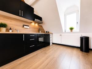 a kitchen with black cabinets and a wooden floor at Les Toits d'Arras in Arras