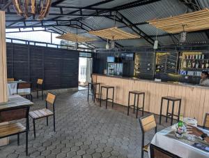 a restaurant with a bar with chairs and tables at Gorilla Trekking Guest House in Ruhengeri
