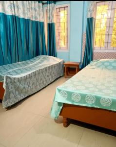 a bedroom with two beds and two windows at D Mukta Lodge in Guwahati