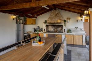 a kitchen with a wooden table and a fireplace at Apartman Sara s vrtom in Vantačići